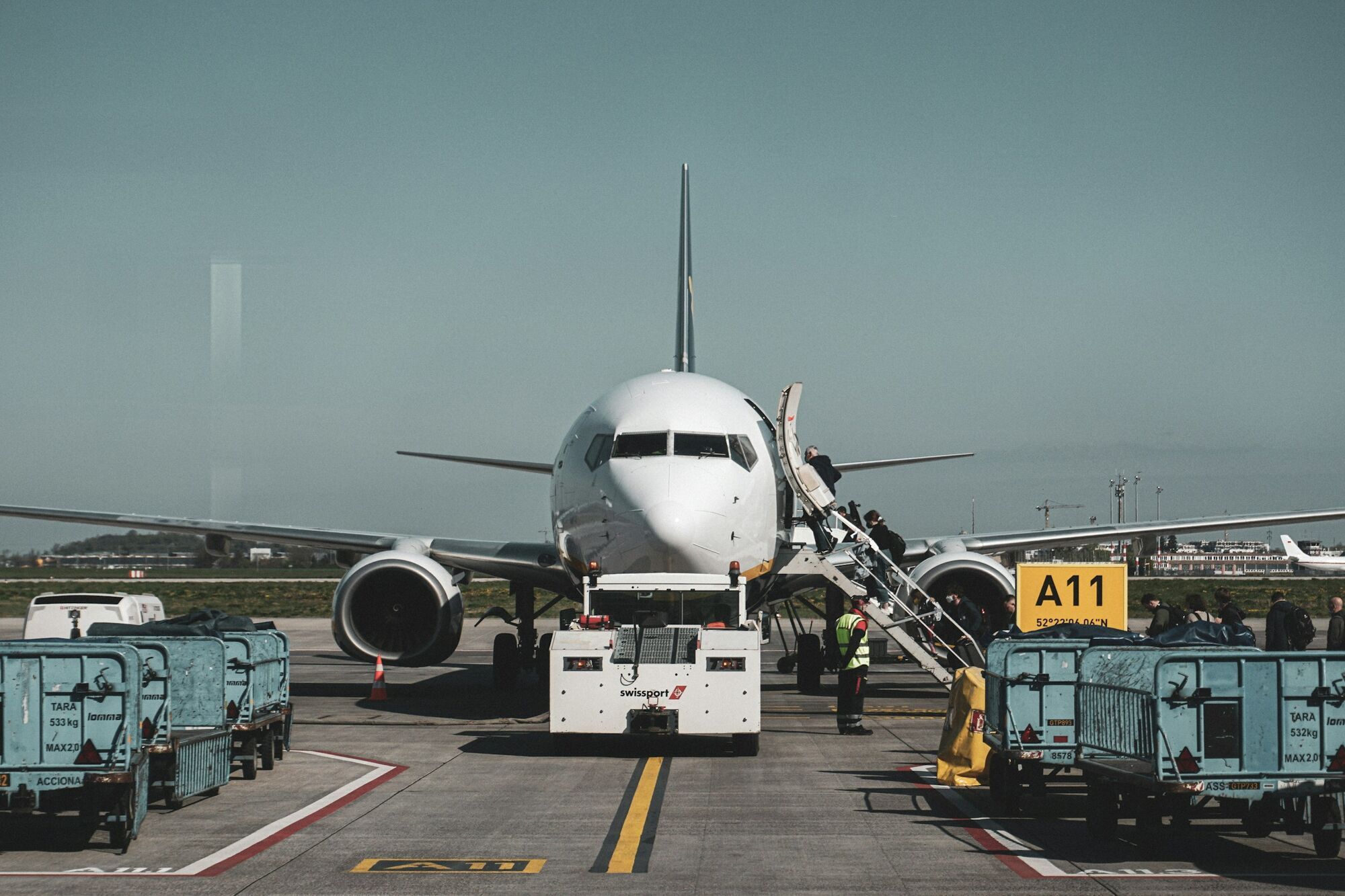 Commercial aircraft parked on runway with ground crew and boarding stairs