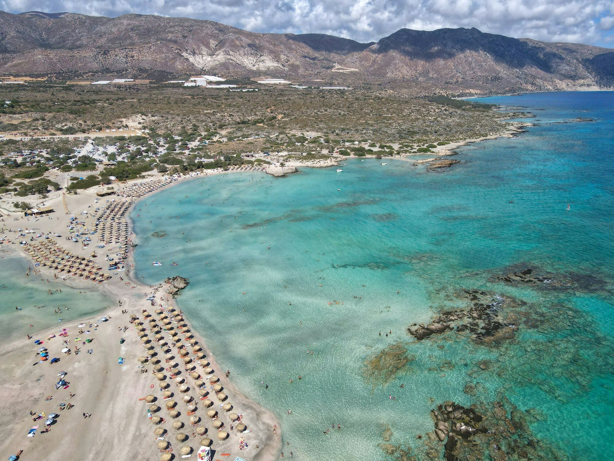 Elafonisi beach in Crete with shallow turquoise lagoon and rows of sunbeds on the sand