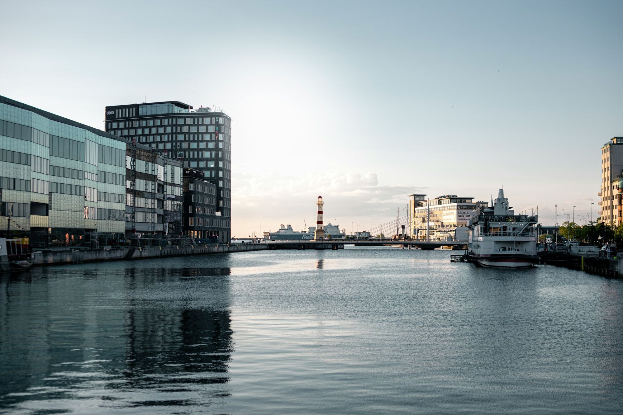 Canal view in Malmö with modern buildings and lighthouse in the distance