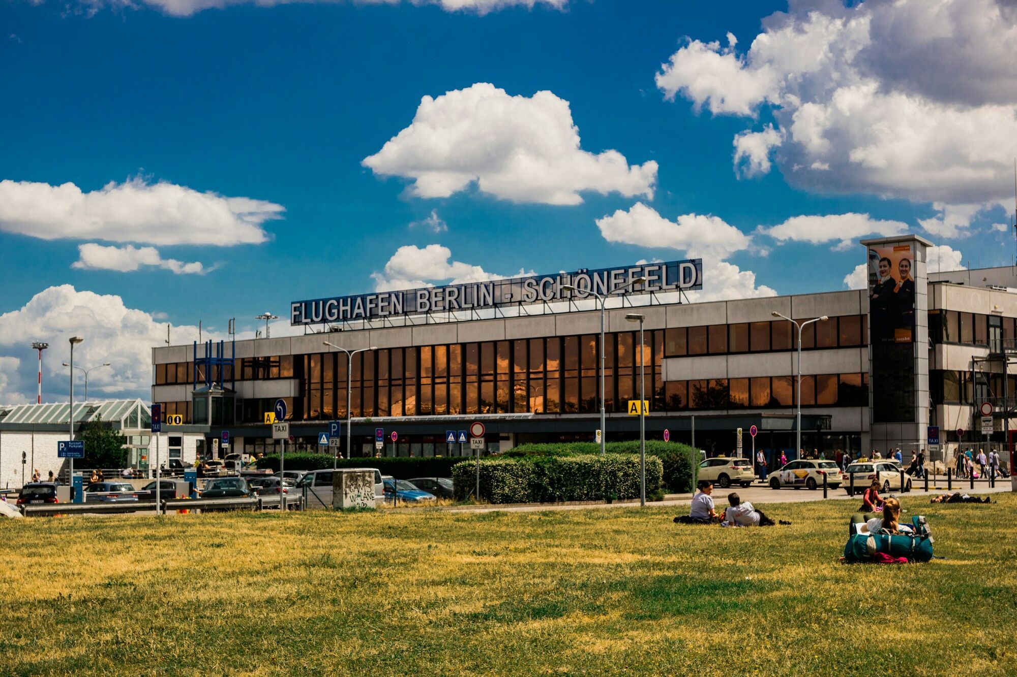 Berlin Schönefeld airport terminal building with people outside on a grassy area