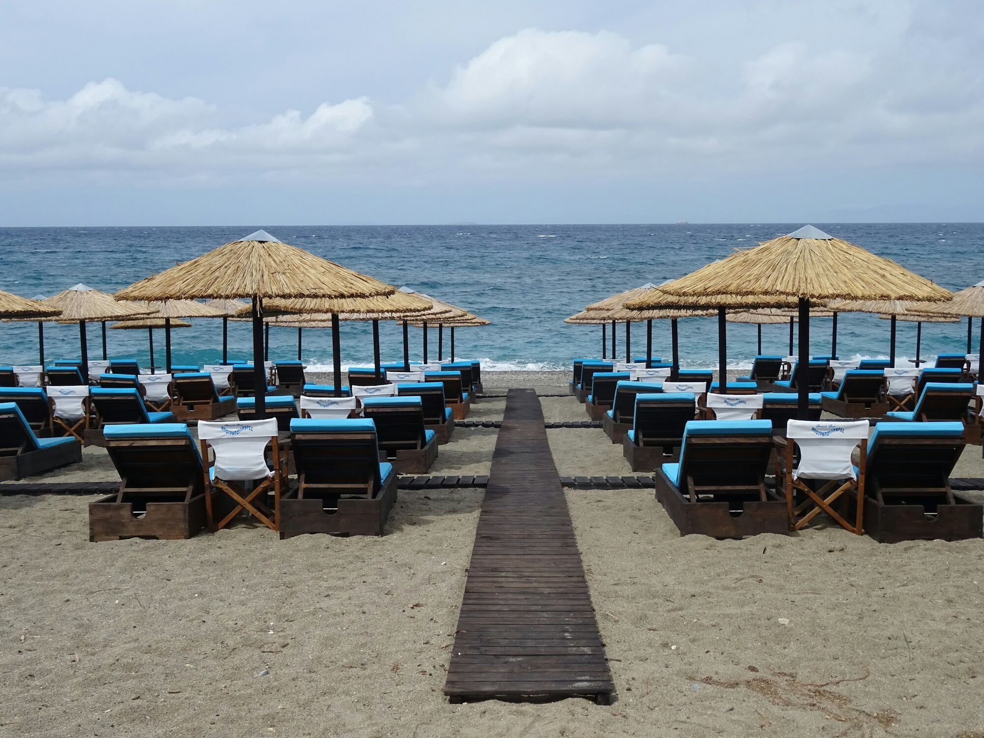 Beachfront with neatly arranged sunbeds and straw umbrellas facing the sea