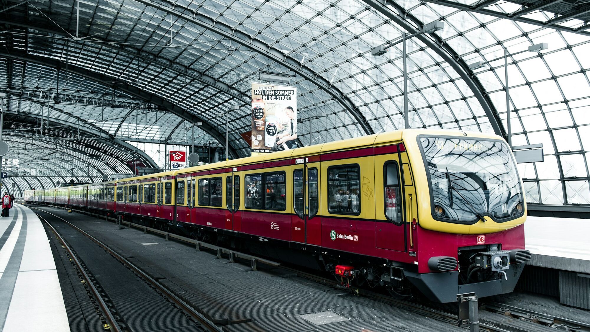 S-Bahn train at a Berlin station platform under a glass roof structure