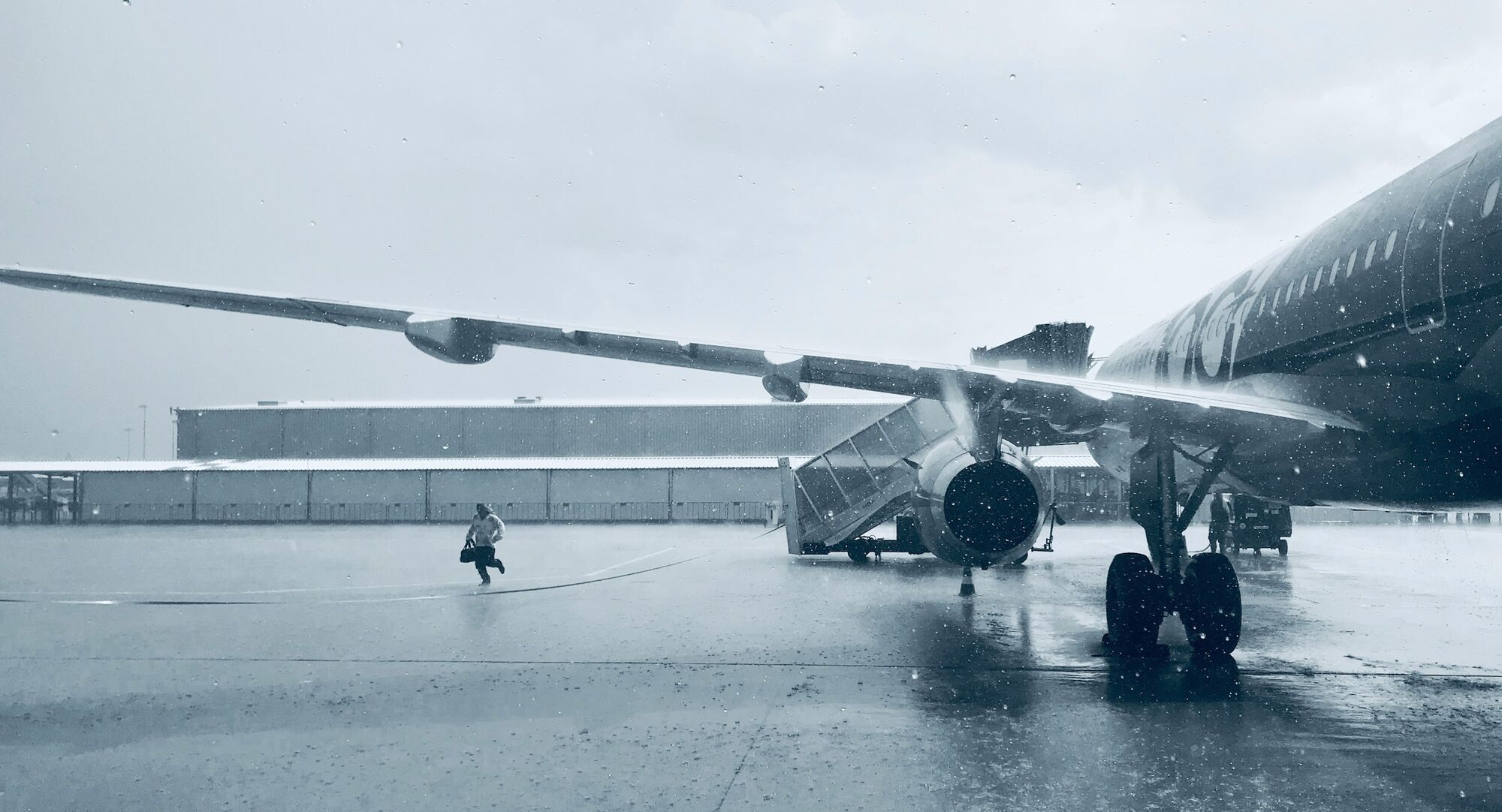 Aircraft on ground during snowfall with crew moving across apron