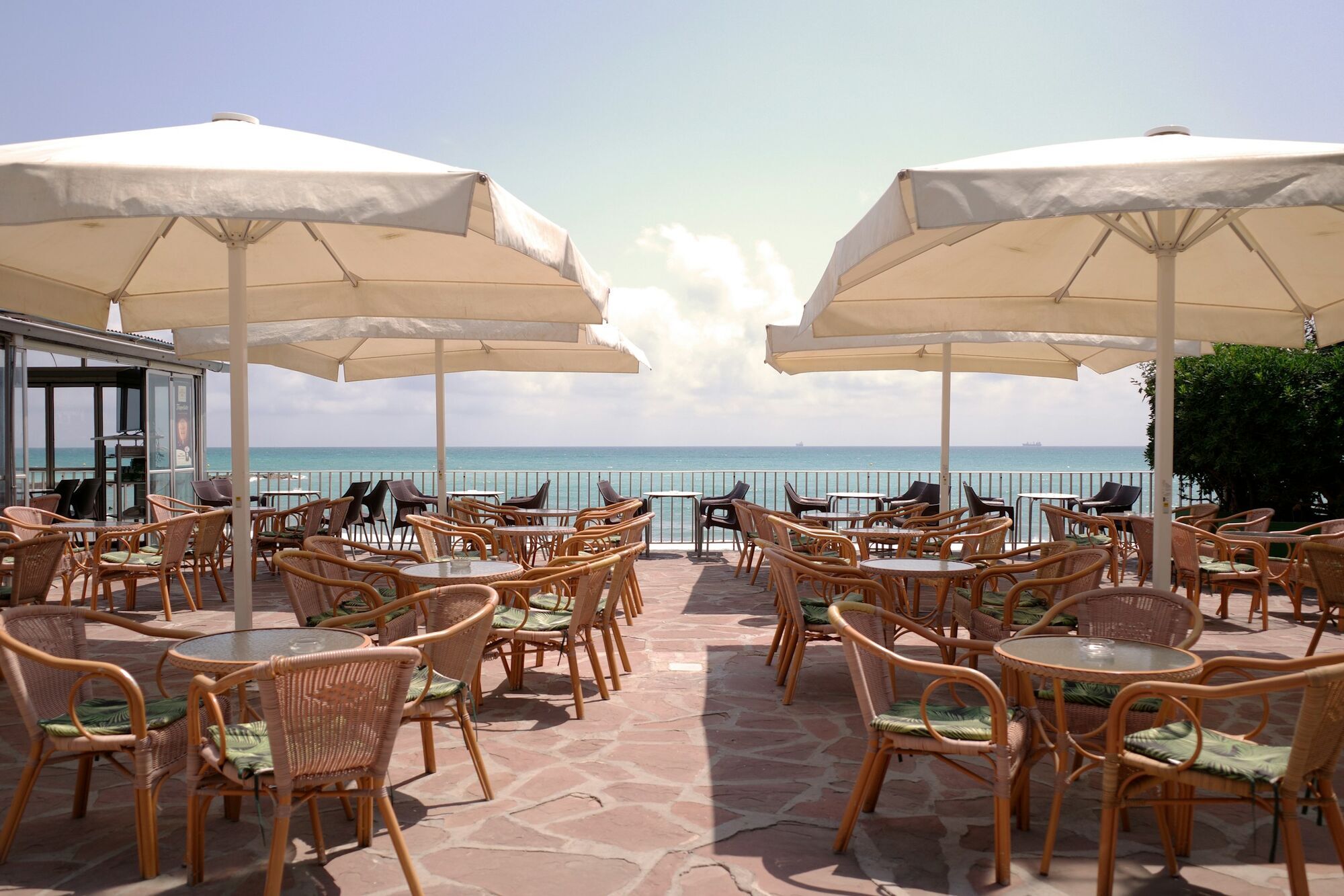 Empty seaside terrace with tables and umbrellas under bright sun