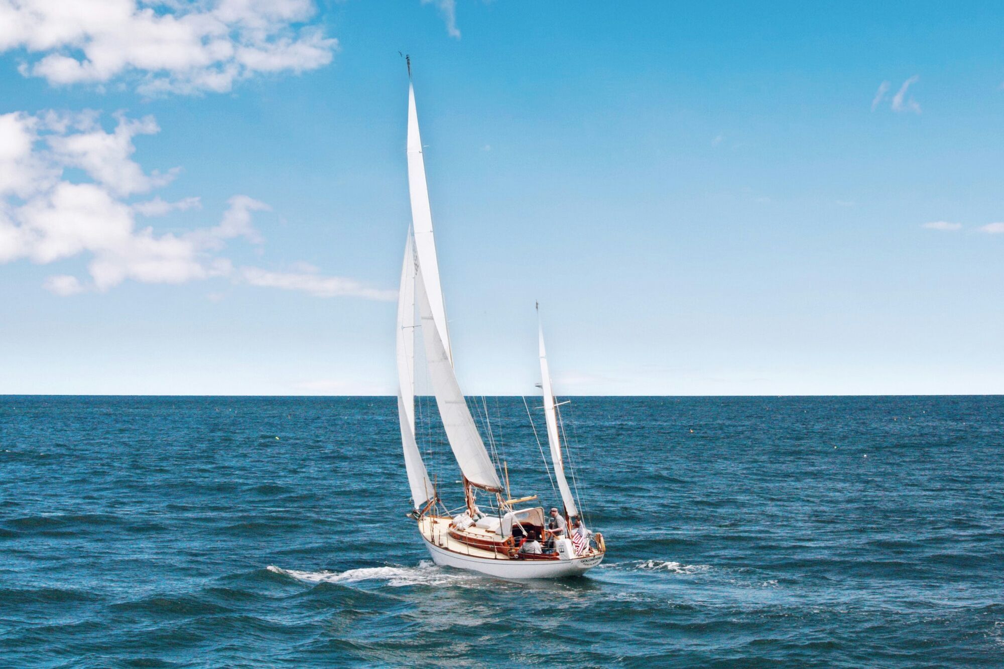 Small sailing yacht on open water under clear sky