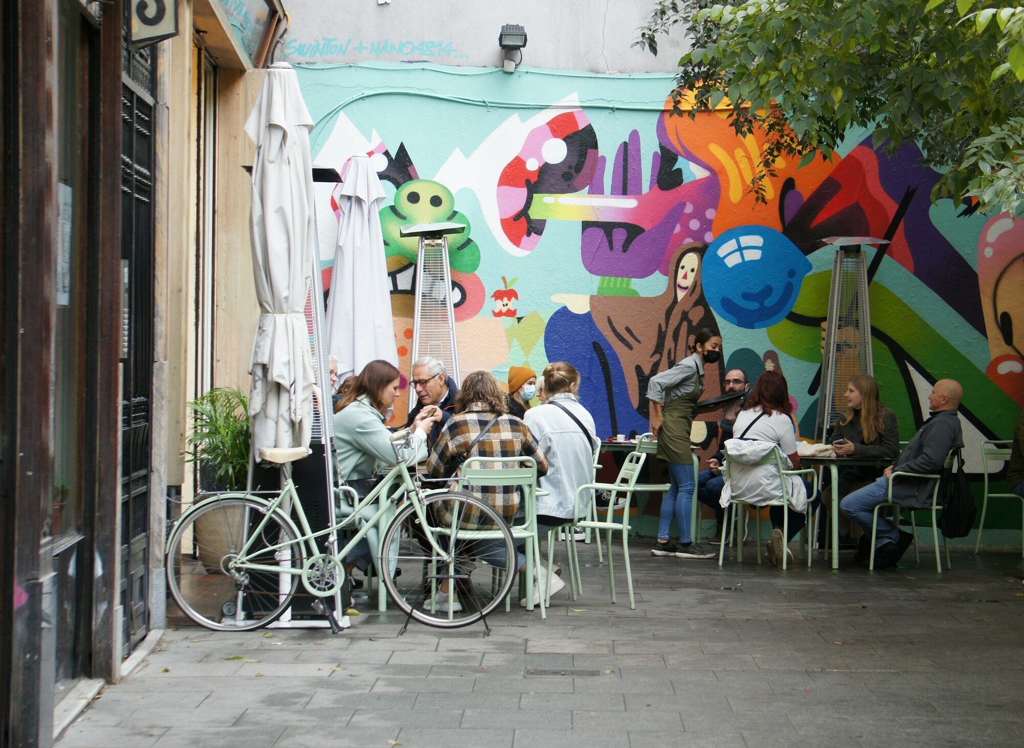 People dining outdoors in a shaded courtyard café