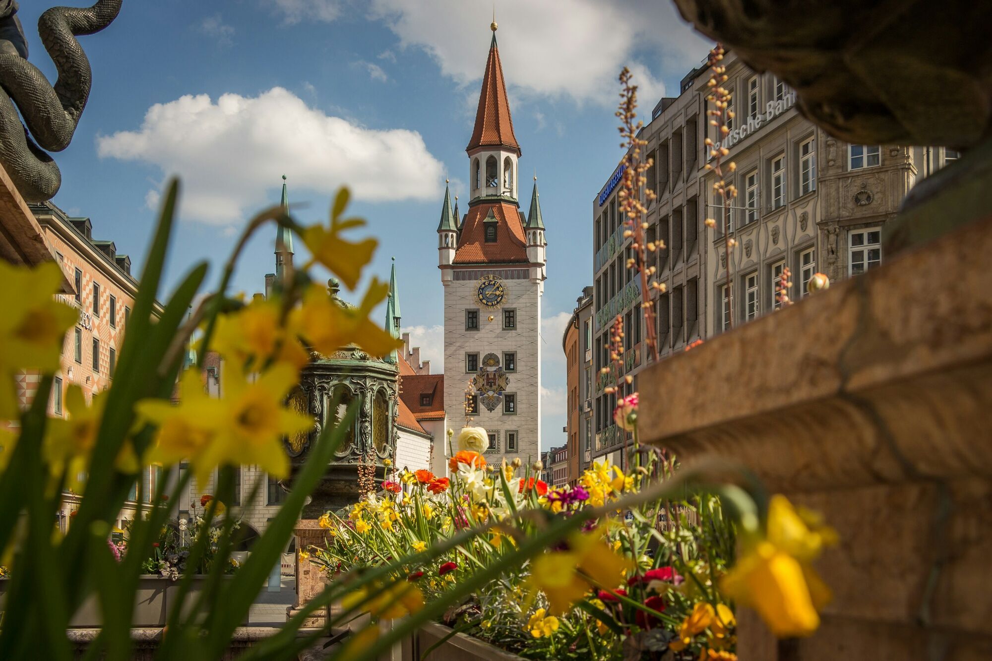 Munich old town street with clock tower and flowers in the foreground