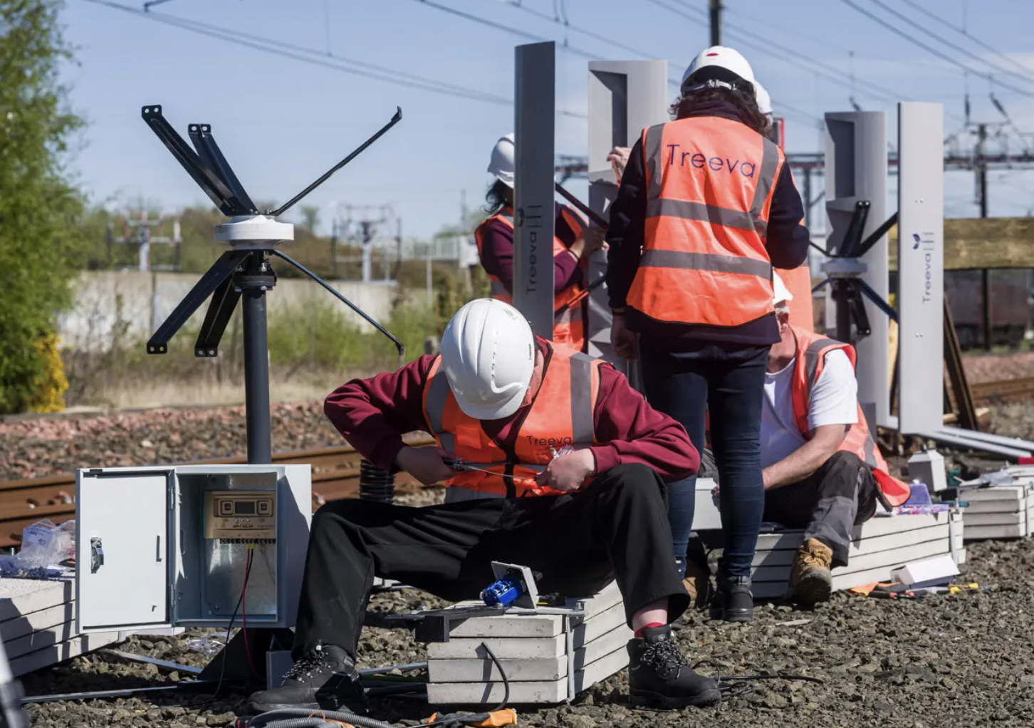 Engineers installing small wind turbines near railway track