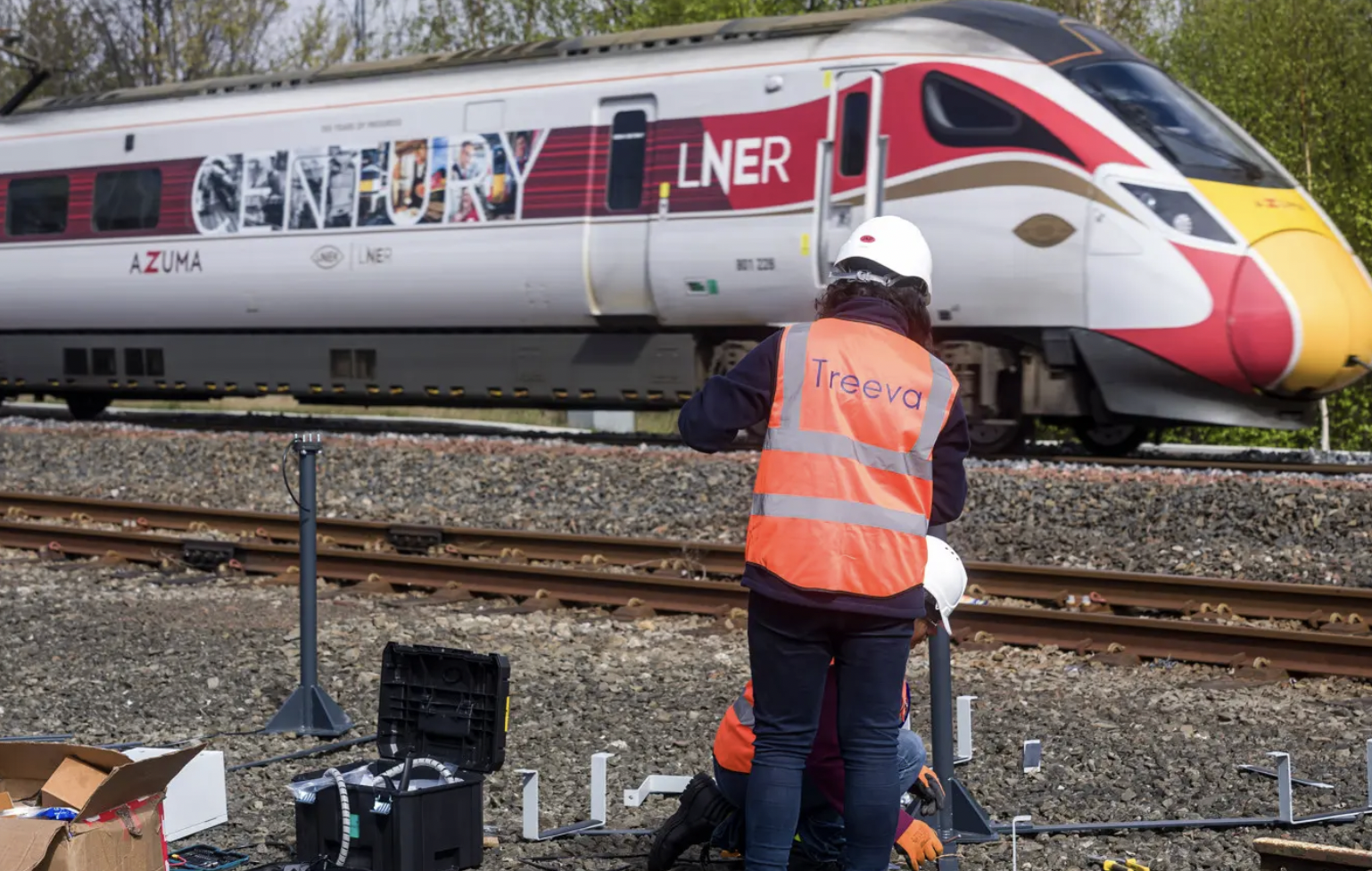 Worker installing turbine unit as LNER train passes