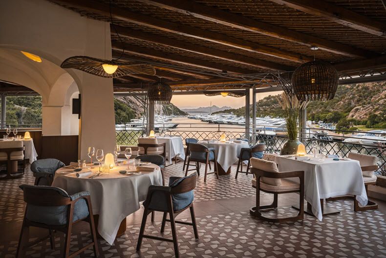 Outdoor restaurant terrace overlooking marina at sunset in Sardinia
