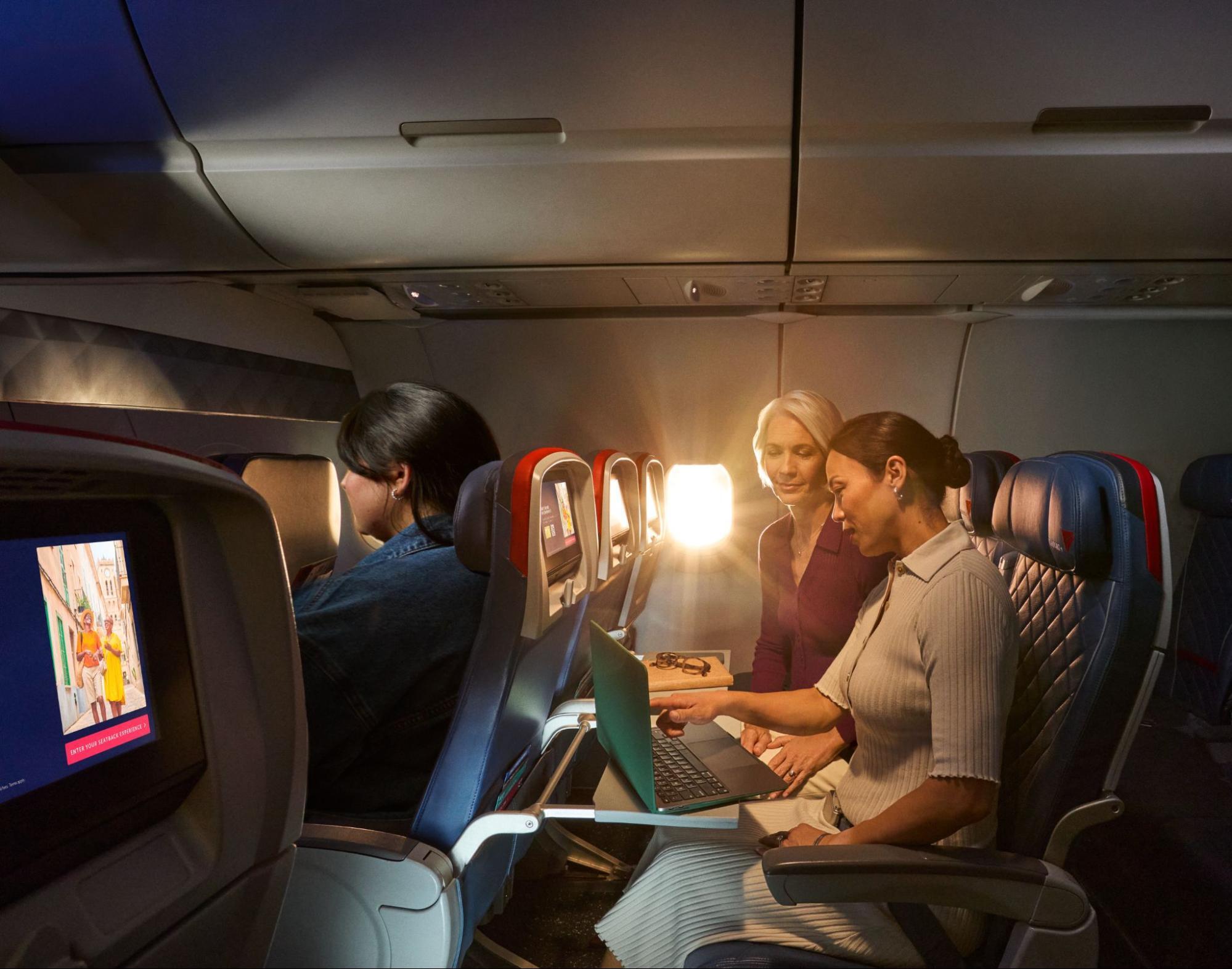 Passengers using a laptop in a Delta aircraft cabin