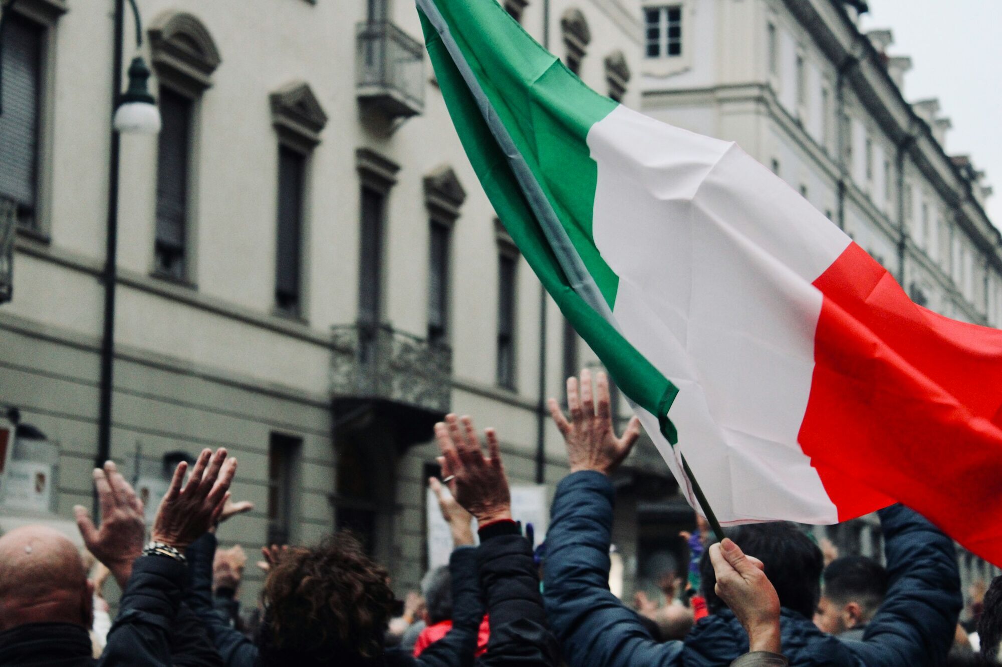 Italian flag raised above a city crowd