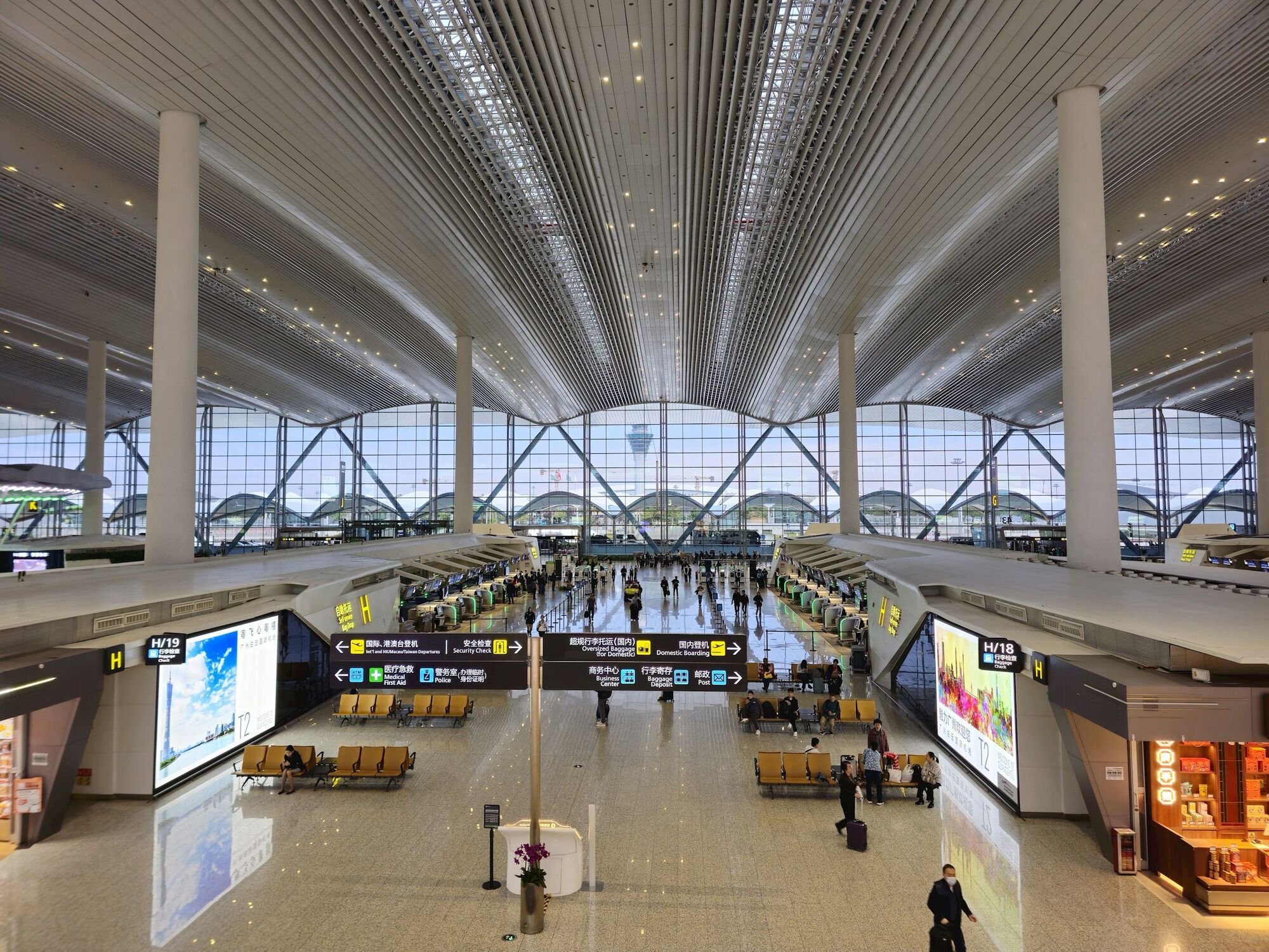 Large modern airport terminal with passengers, check-in desks and high ceilings