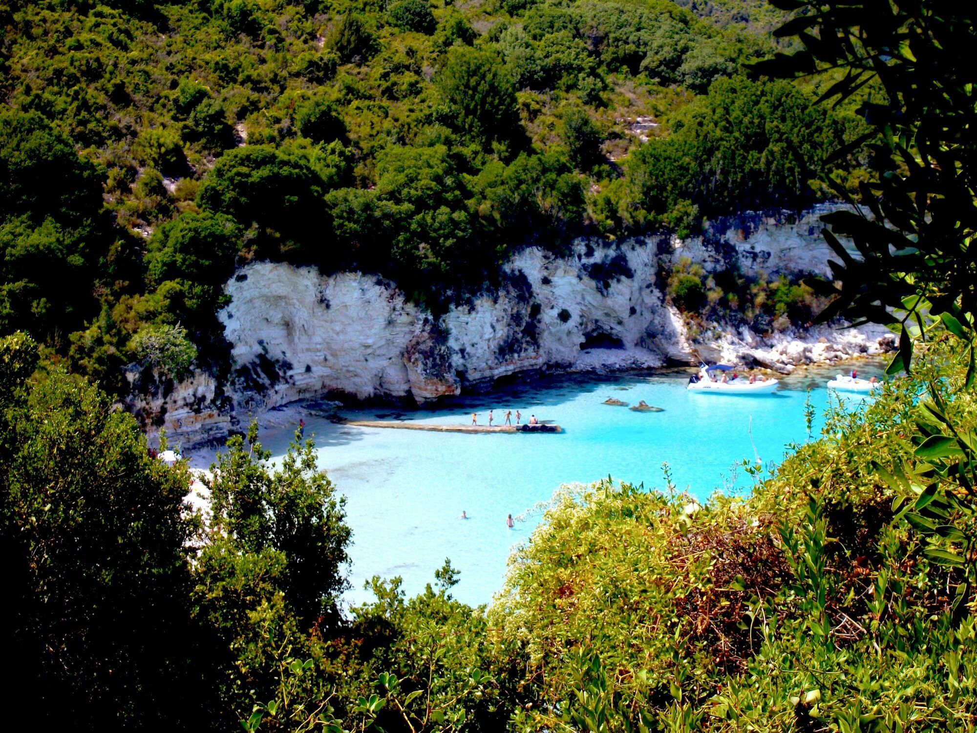 Turquoise cove in Greece surrounded by cliffs and green trees