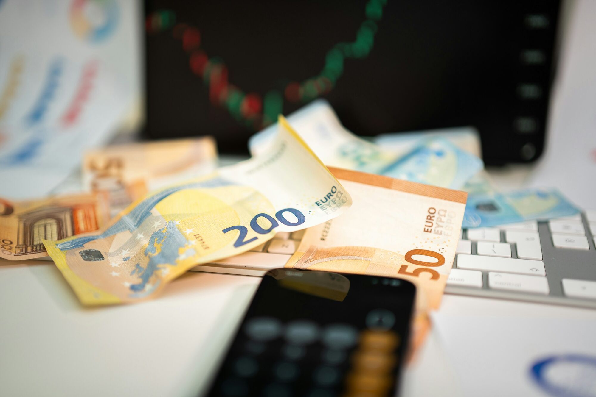 Euro banknotes and calculator on desk