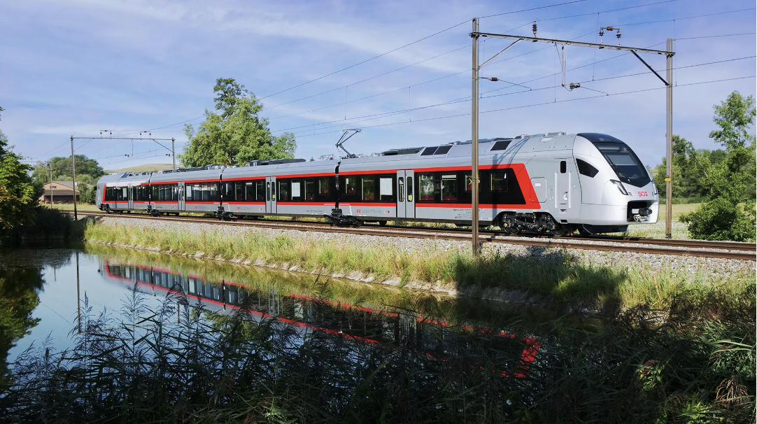 Modern Stadler train travelling beside a canal