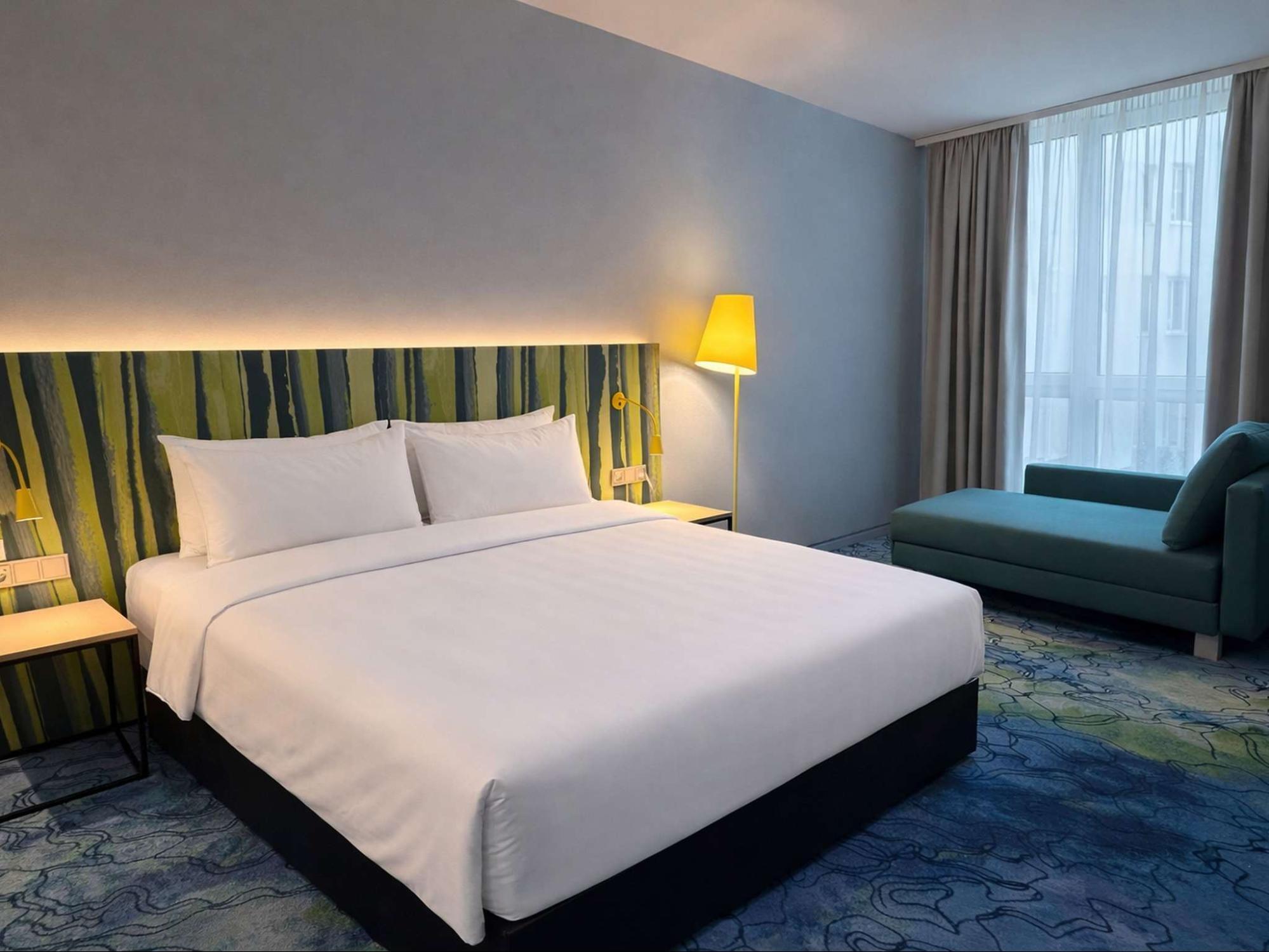 Guest room at ibis Styles Munich Airport with a double bed and blue-green design