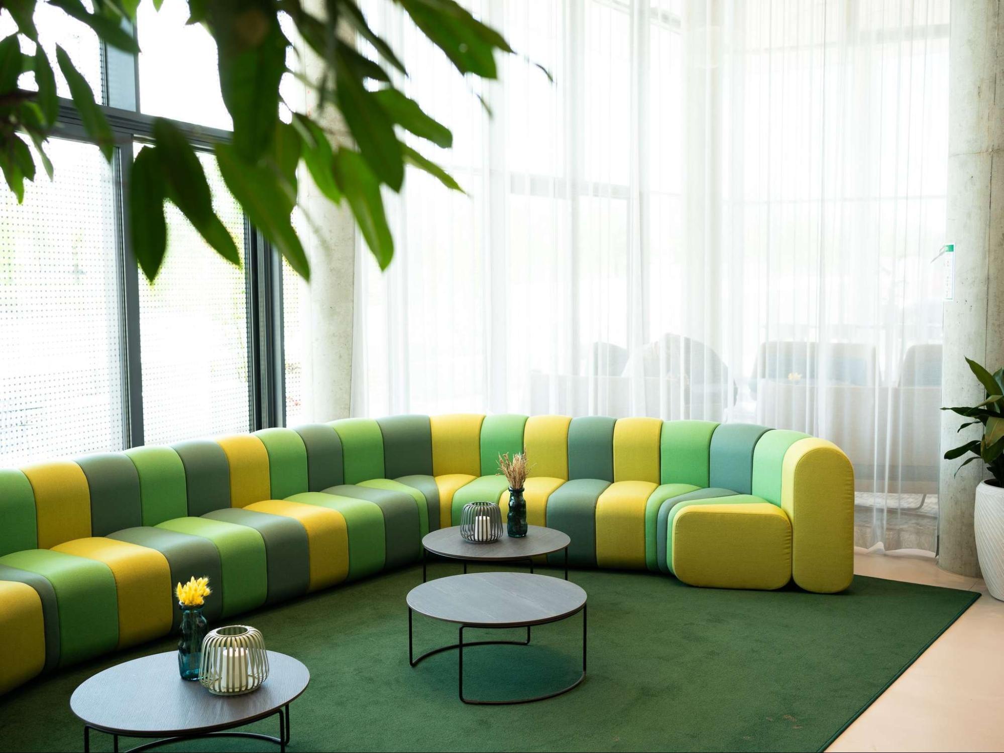 Bright lounge area inside ibis Styles Munich Airport with green and yellow seating