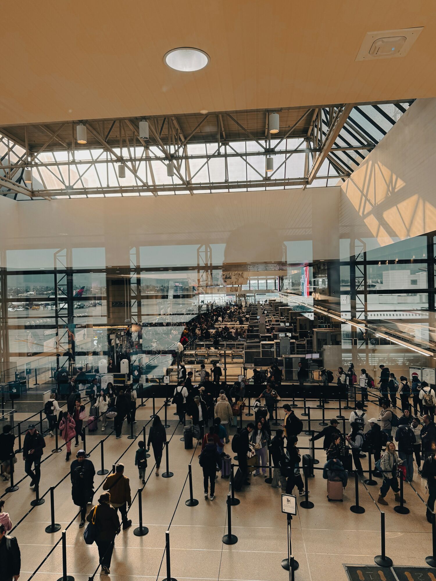 Travellers queuing inside a busy airport security hall