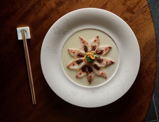 Nobu-style sashimi dish served on a white plate with chopsticks