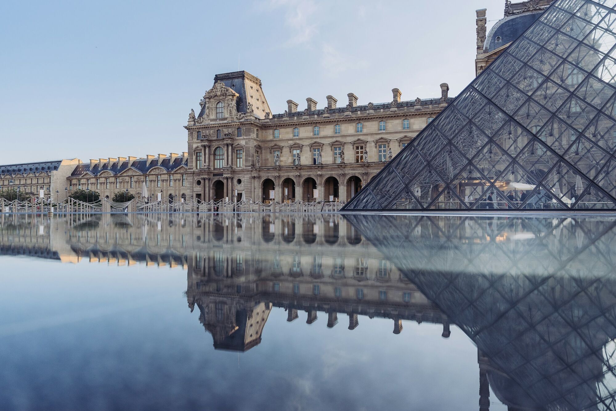 Louvre Museum and glass pyramid reflected in water in Paris