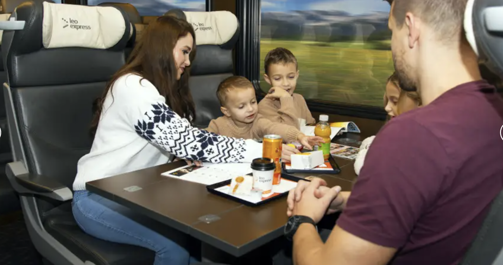 Family seated at a table inside Leo Express train