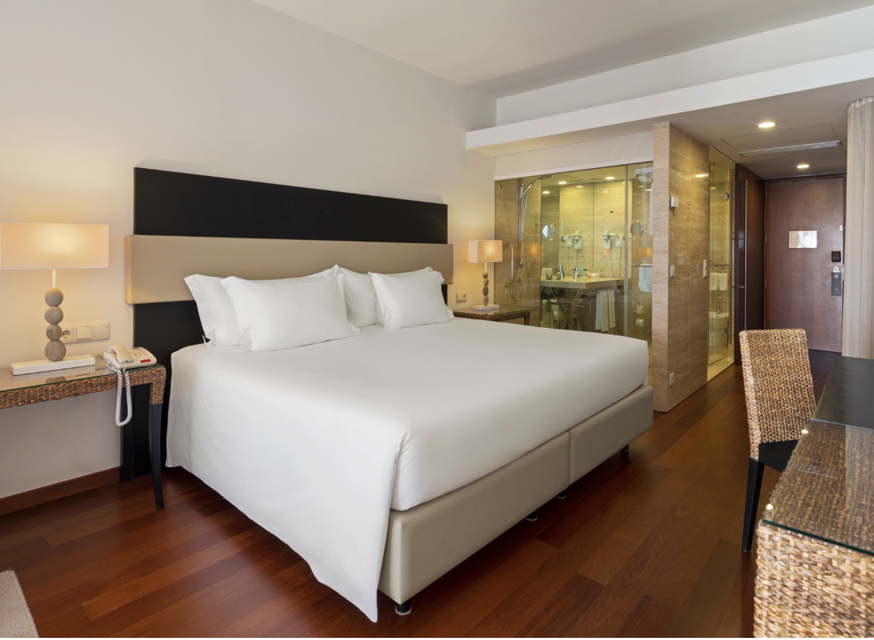 Hotel room with a white bed and glass bathroom