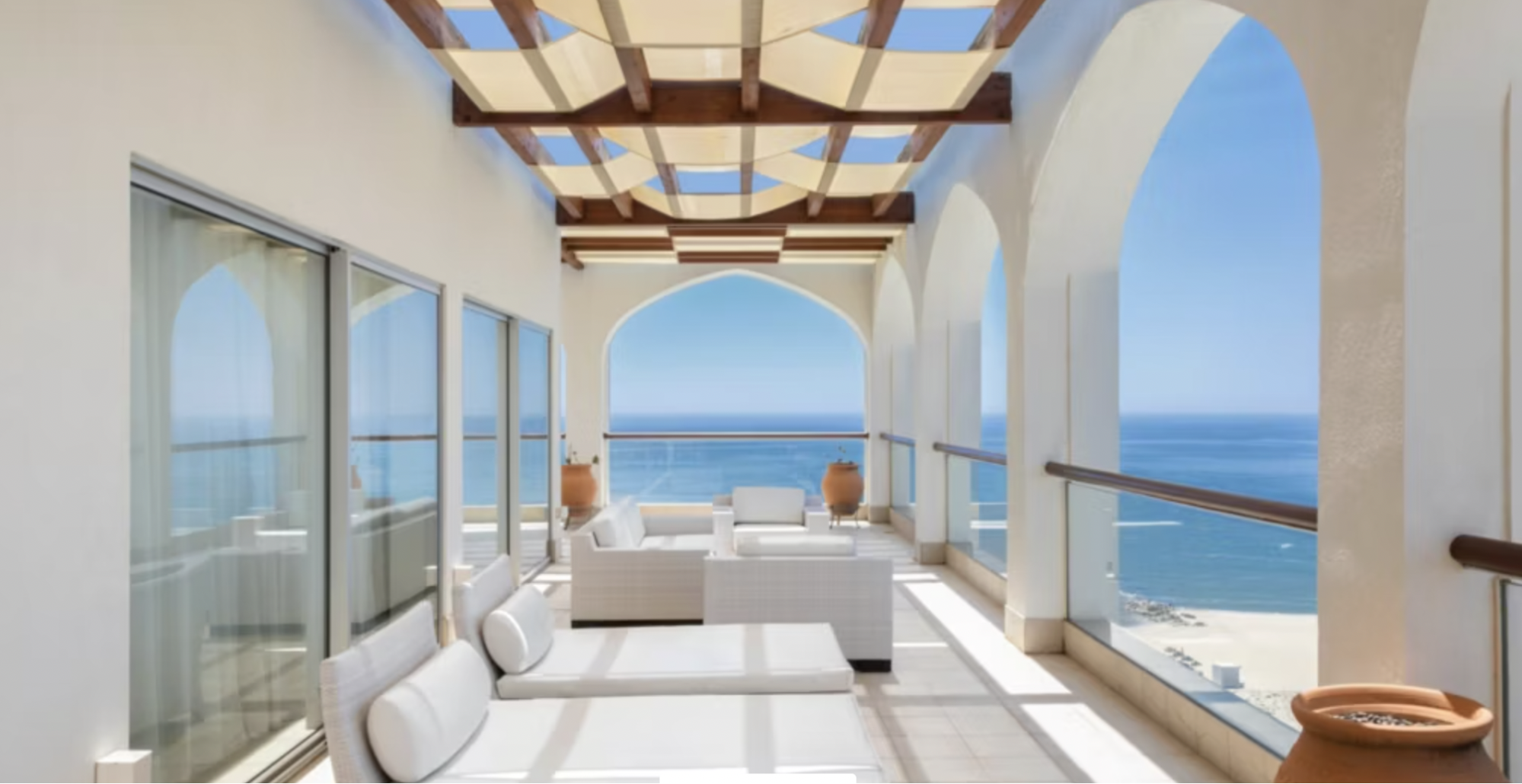 Sea-view hotel terrace with white seating and arched openings