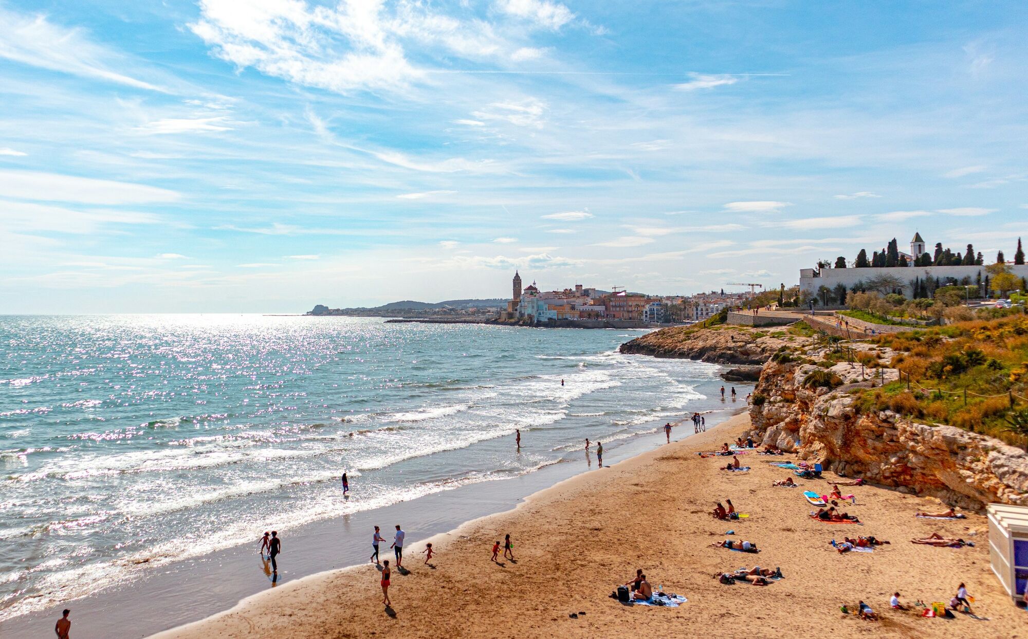 People relaxing on a beach near a coastal town in Europe