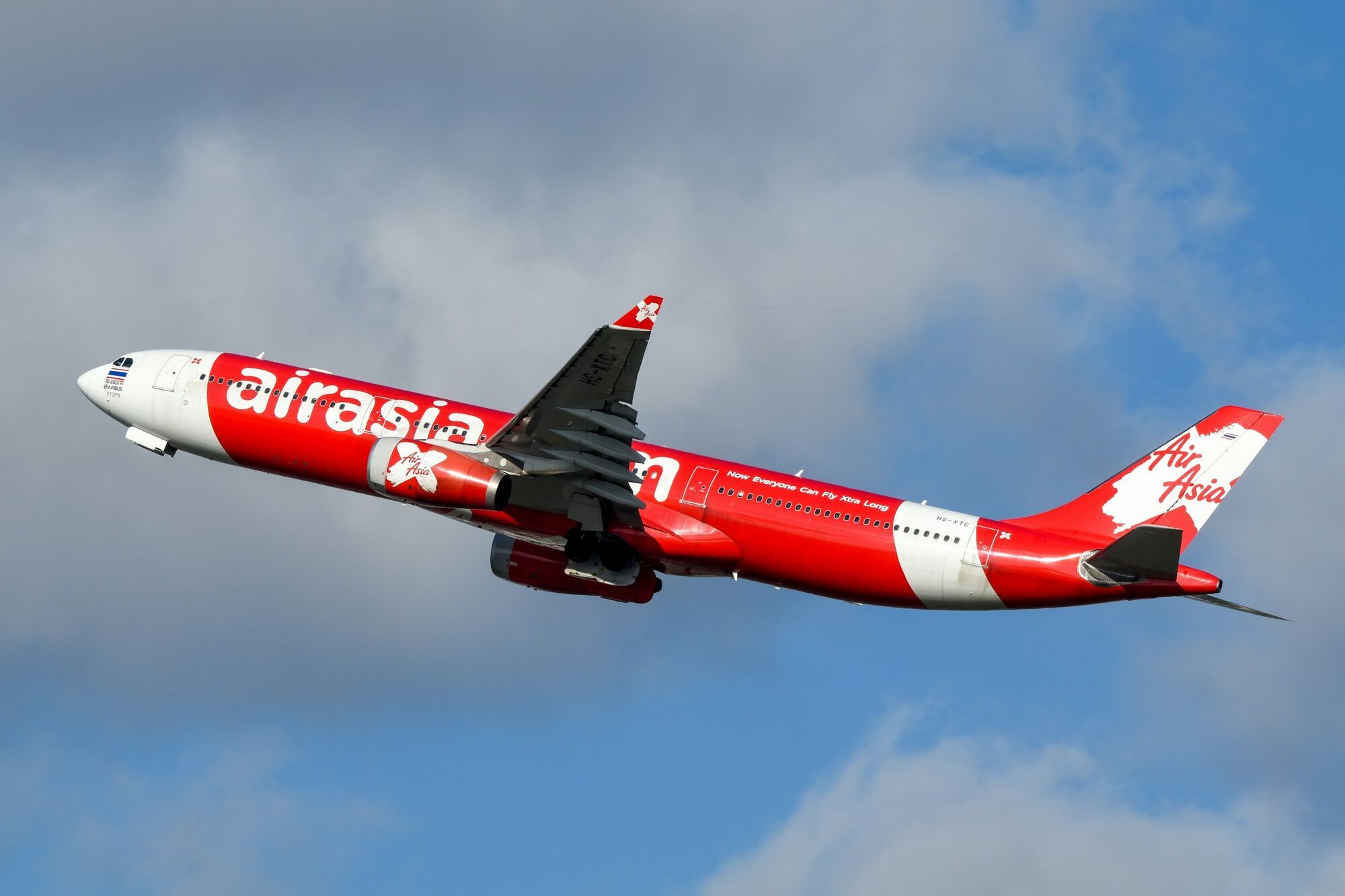 AirAsia aircraft flying through a cloudy sky