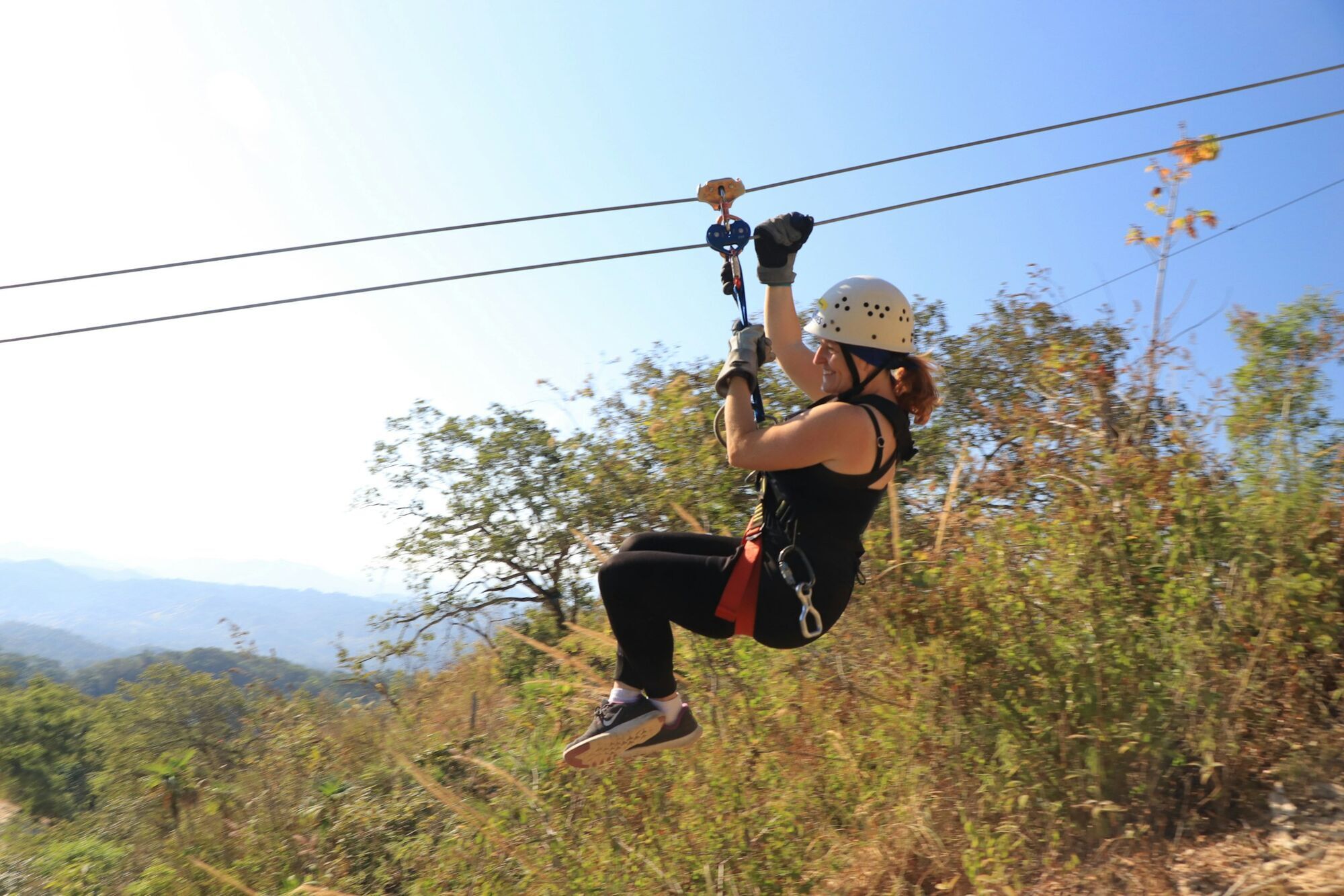 Person riding a zipline through a forest