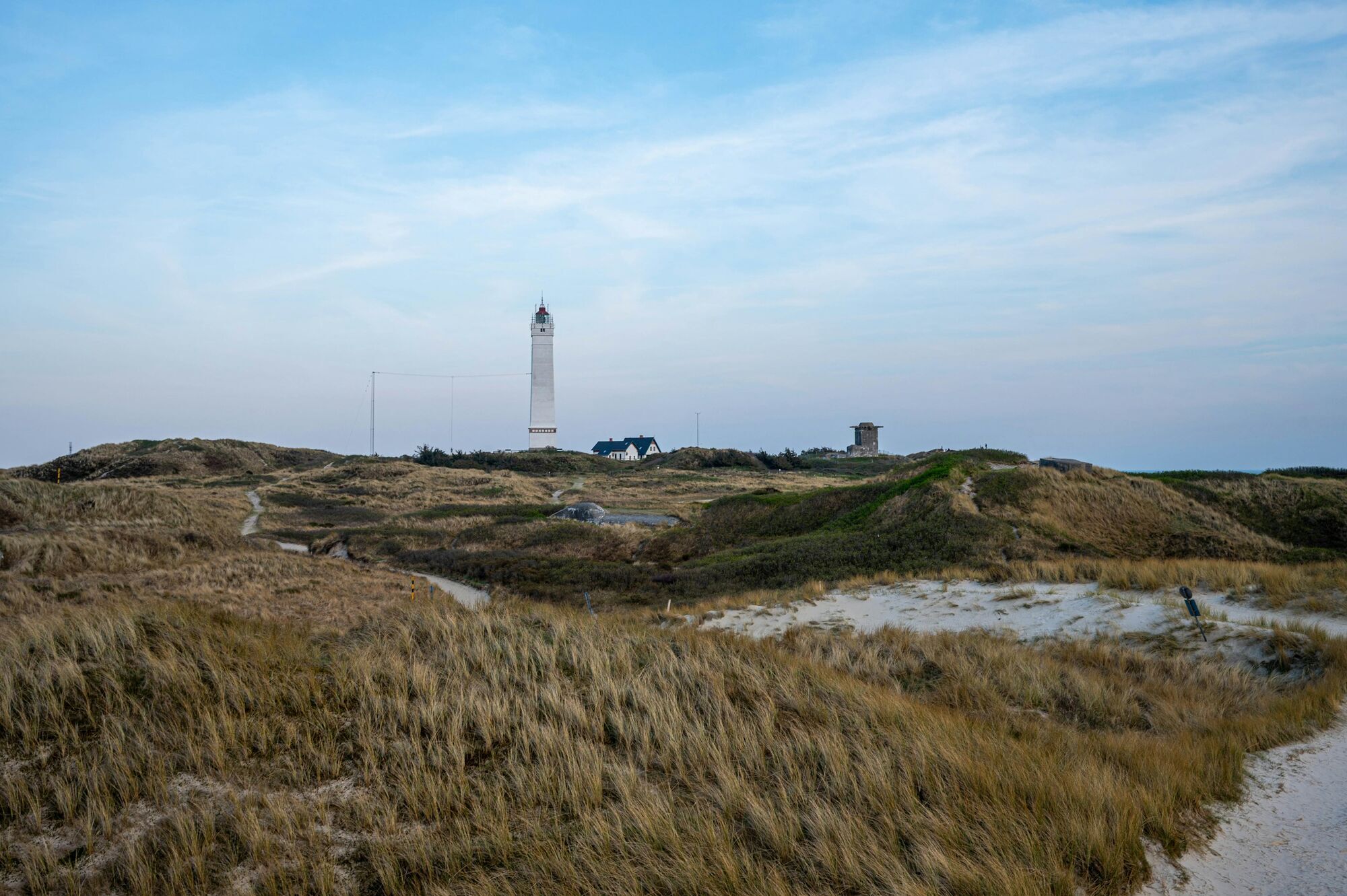 Blåvandshuk Lighthouse beyond coastal sand dunes
