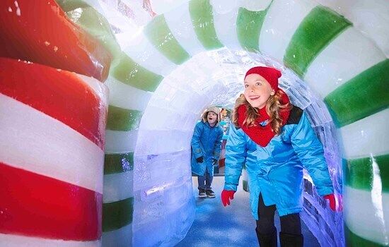 Children walking through a colourful Christmas ice tunnel