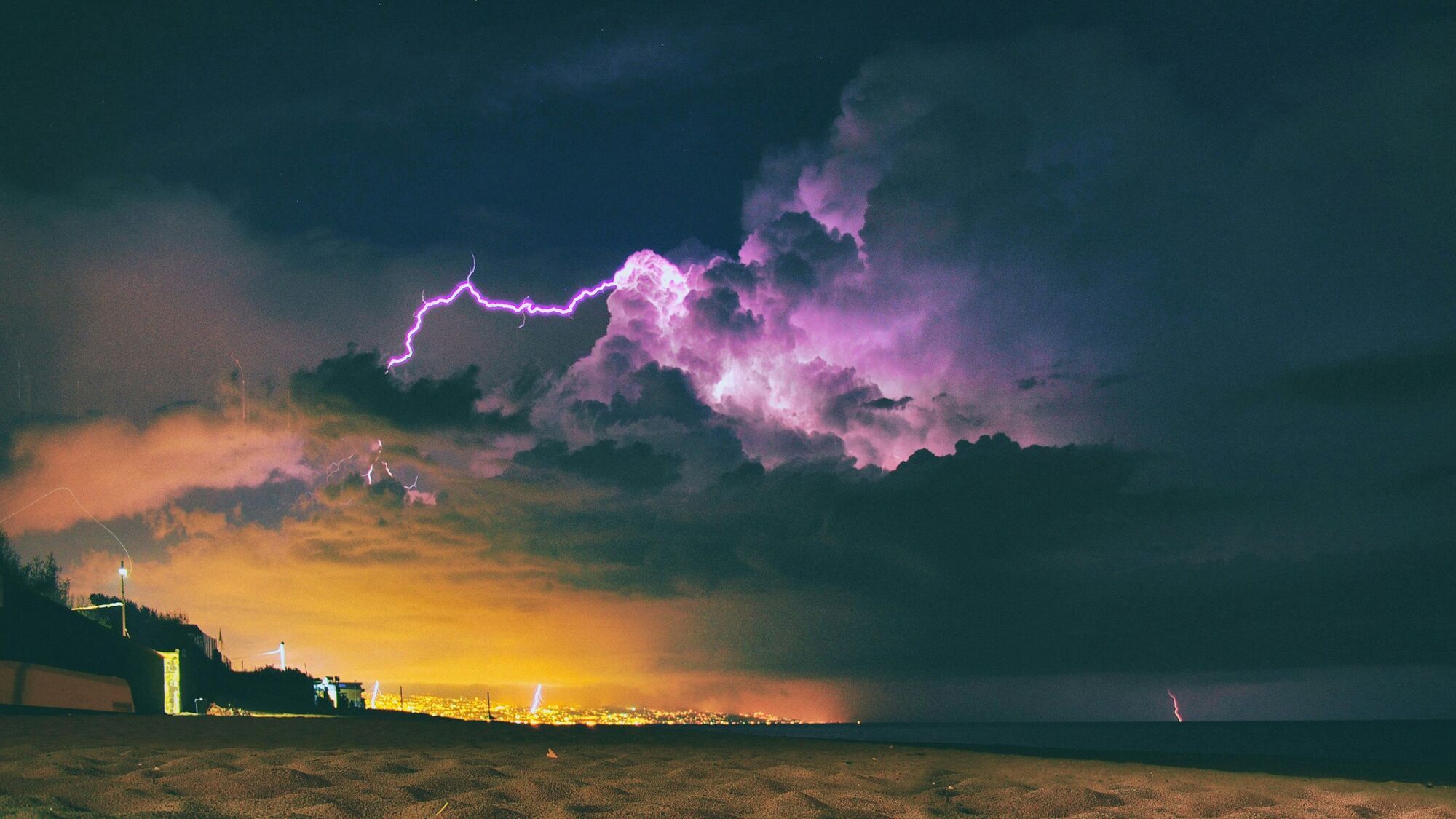 Lightning over a coastal city at night
