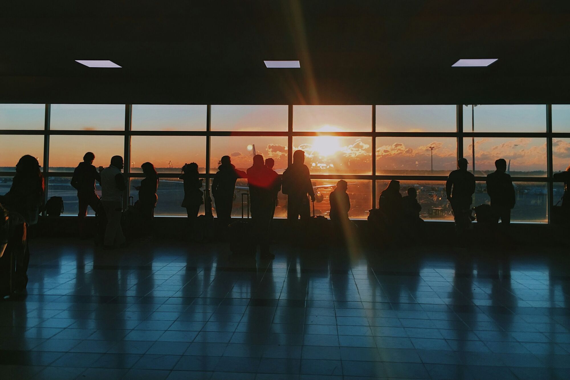 Passengers waiting inside airport terminal at sunset