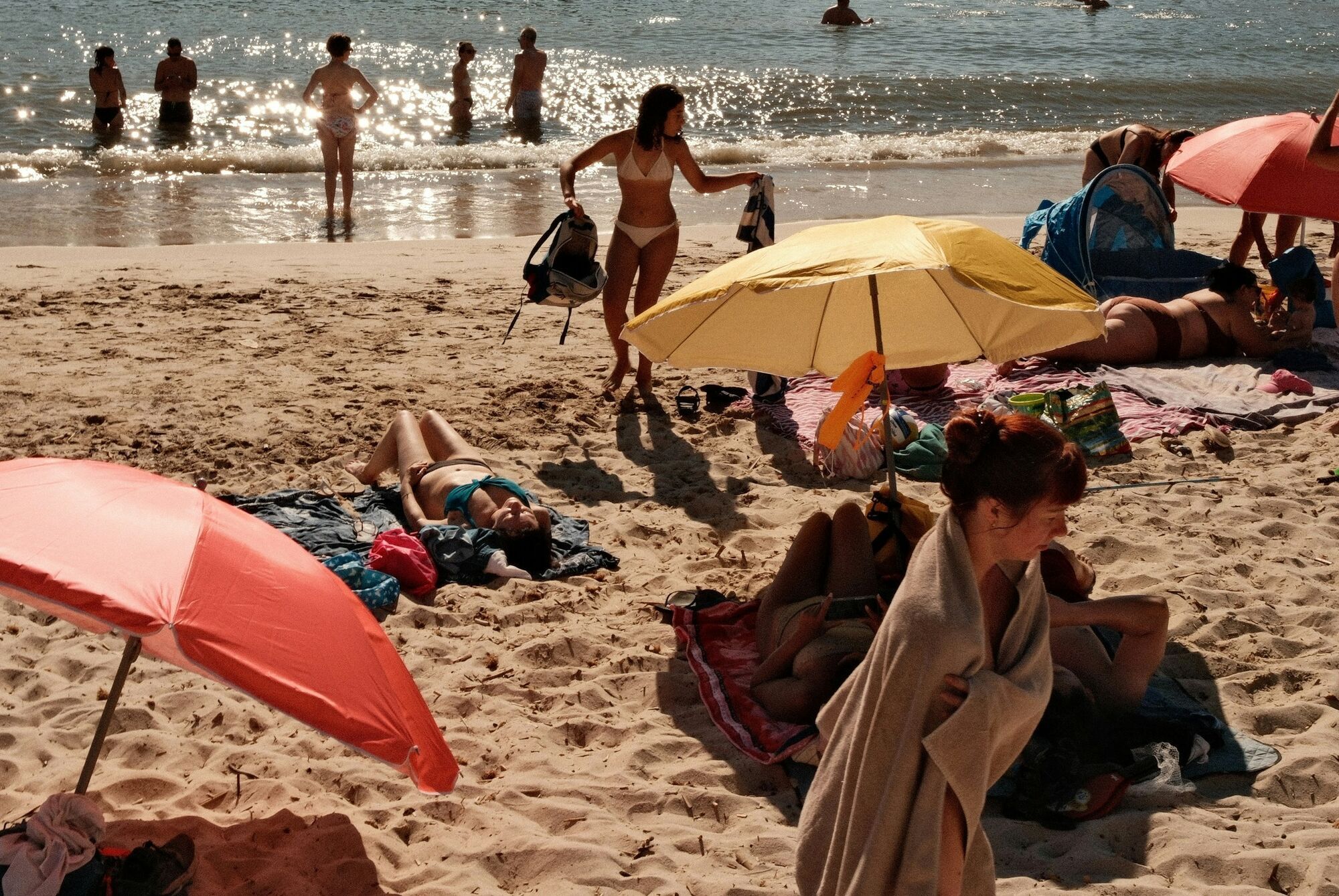 Beachgoers relaxing under parasols by the sea