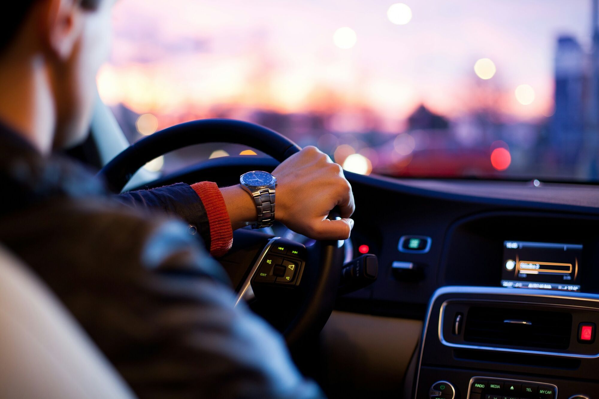 Driver holding the steering wheel at sunset