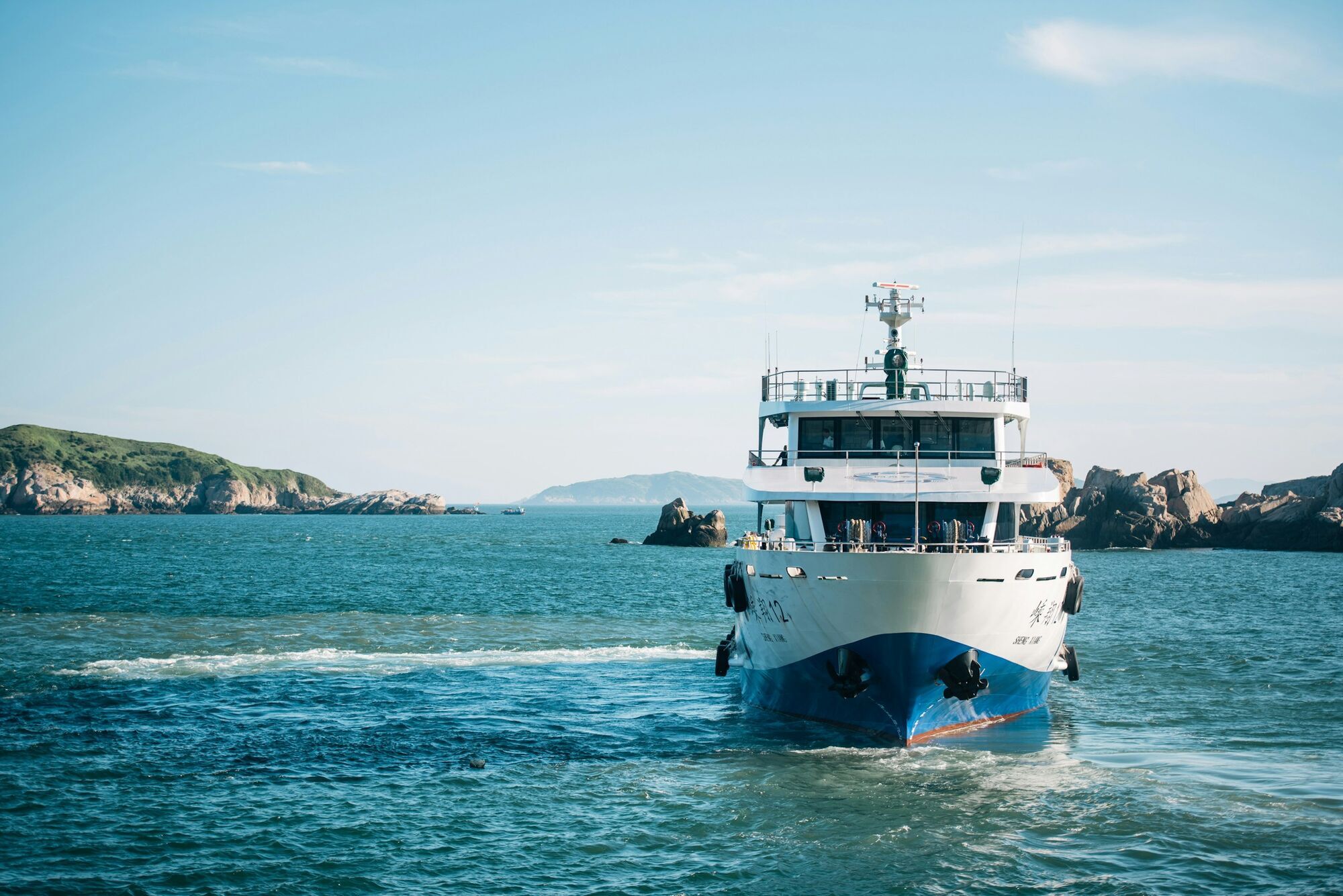 Passenger ferry sailing near a rocky coast