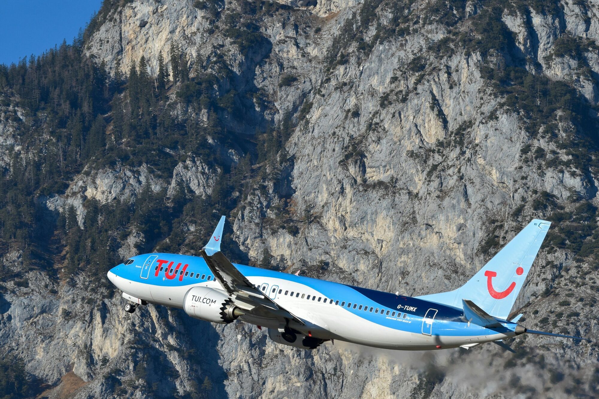 TUI Airways plane flying past Alpine mountains