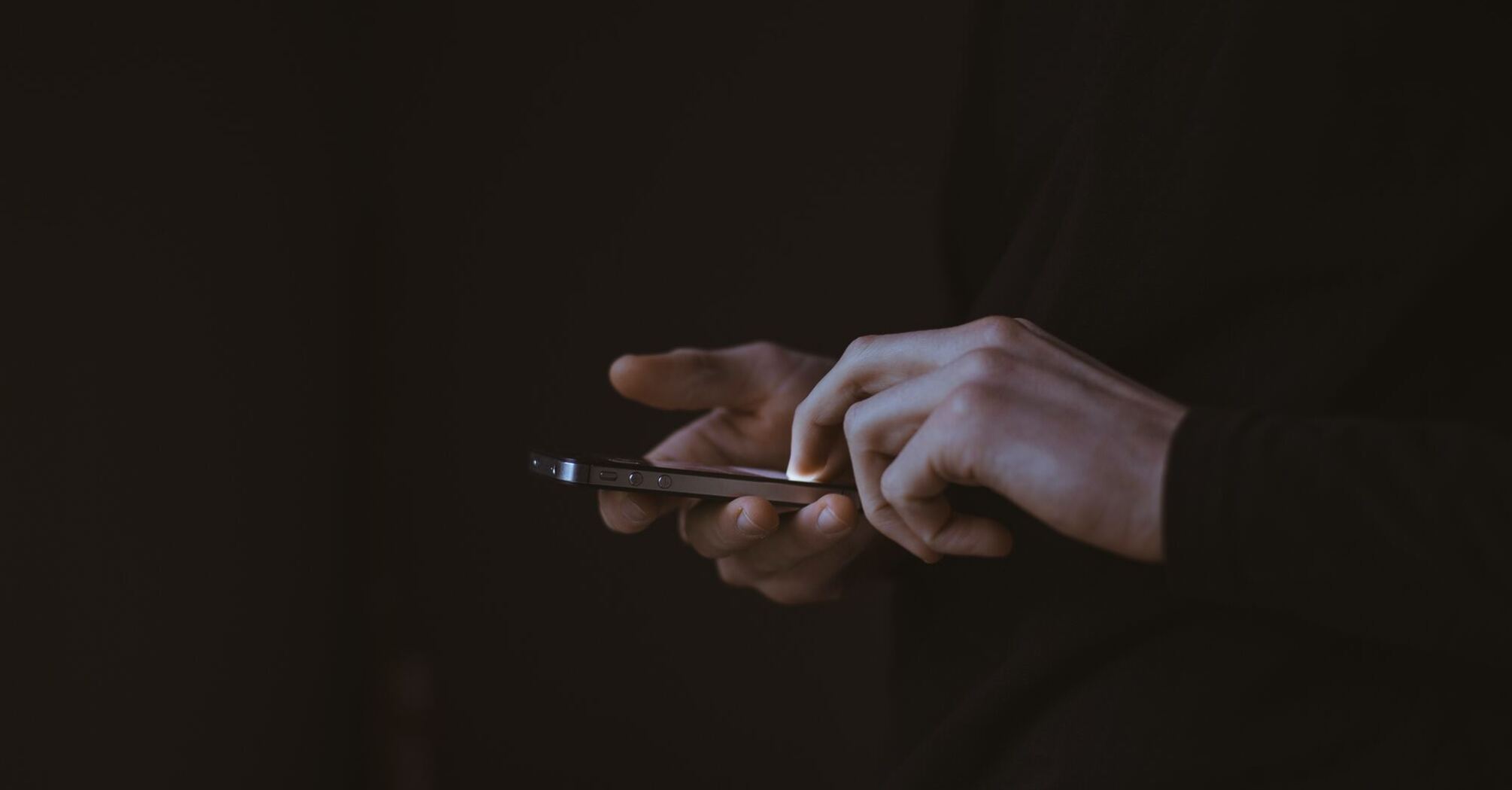 Phone in hands on a dark background