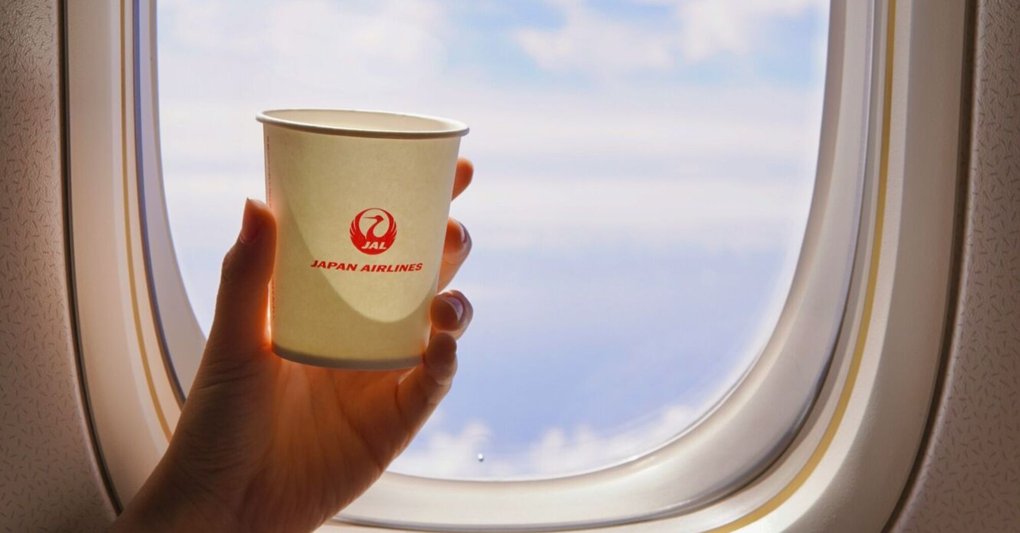 Person holding Japan Airlines disposable cup
