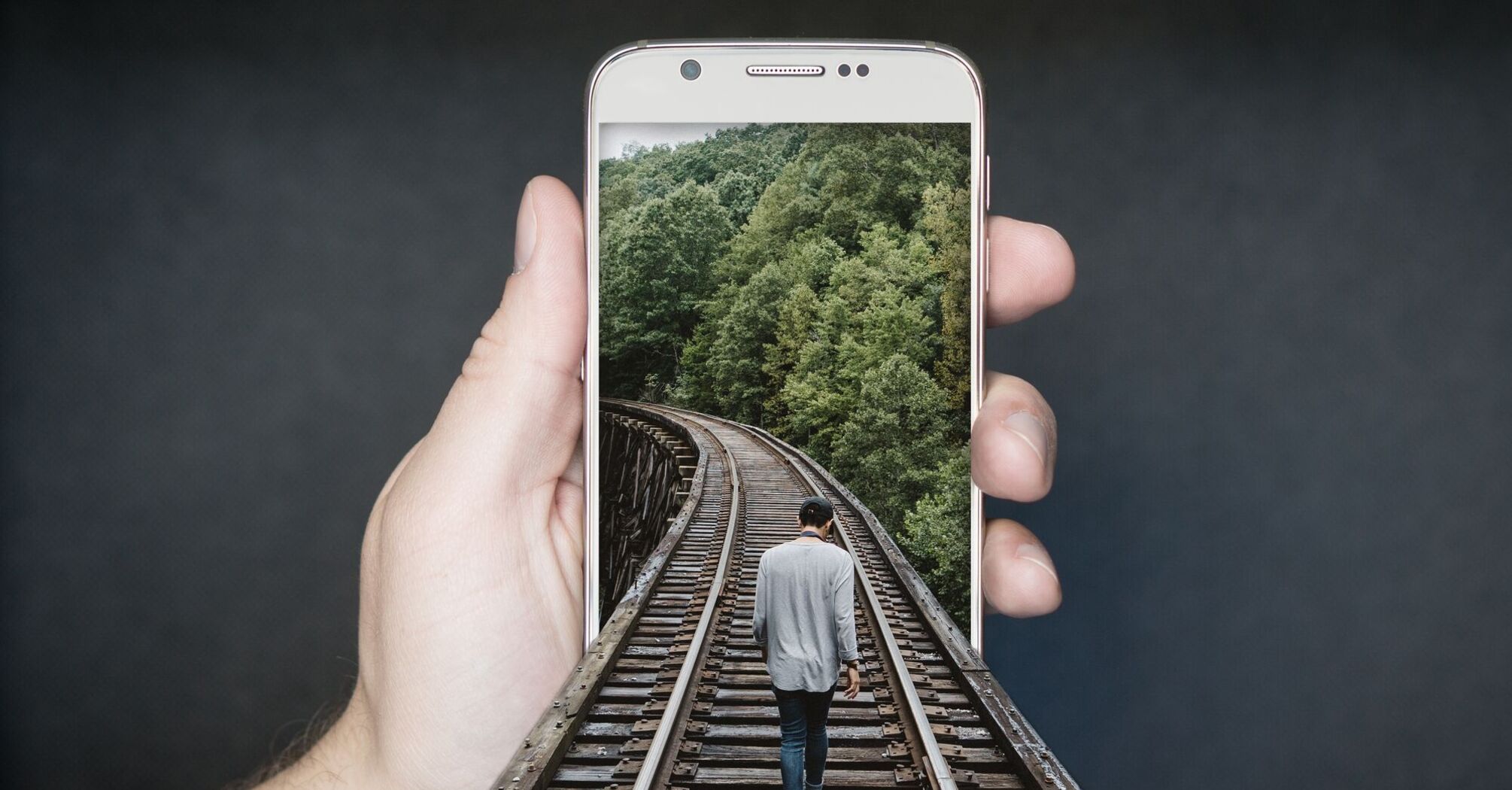 A man walking along a forested railway track, merging digital and physical realms of exploration