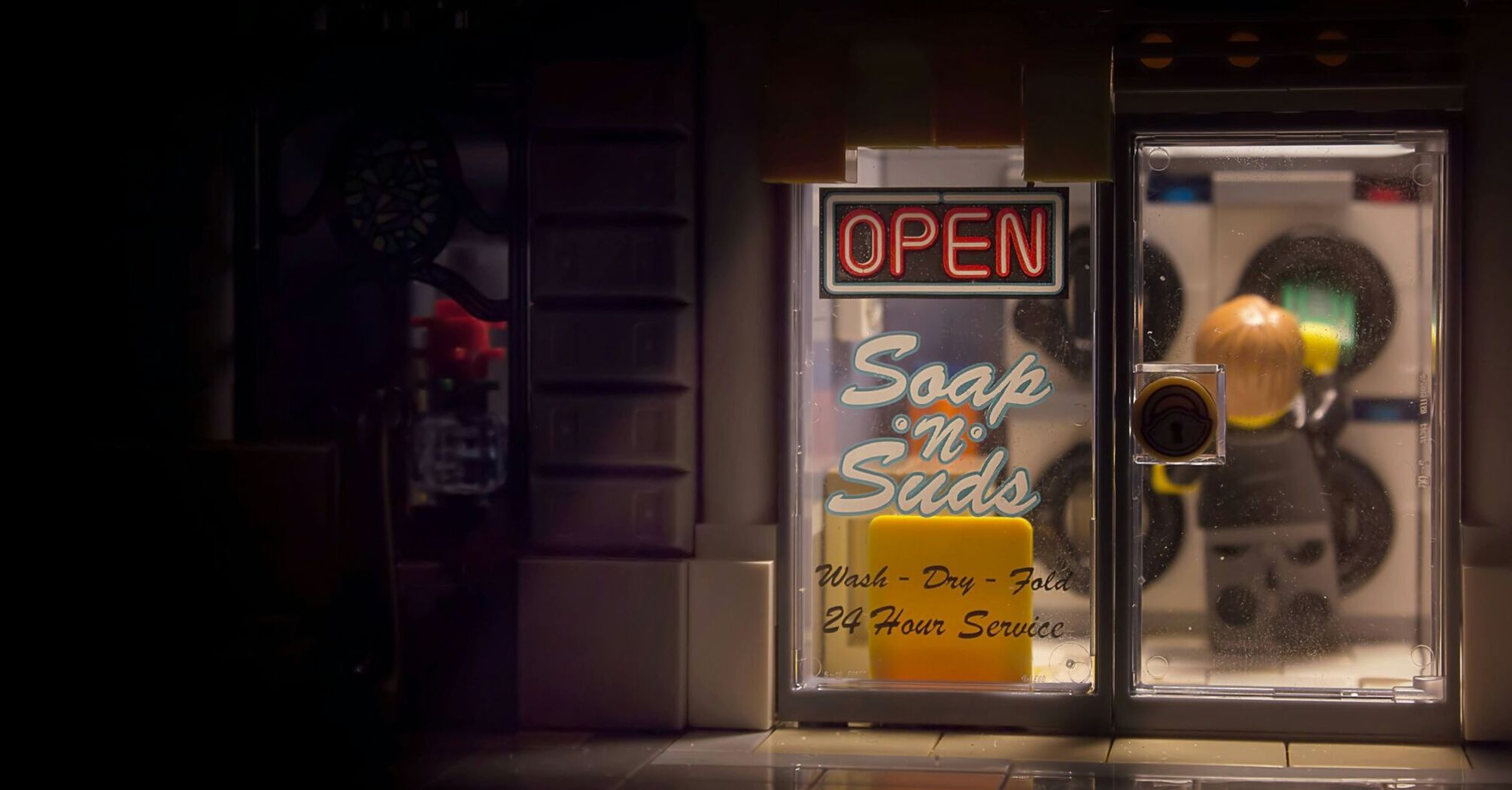A warmly lit storefront window at night with a neon 'OPEN' sign