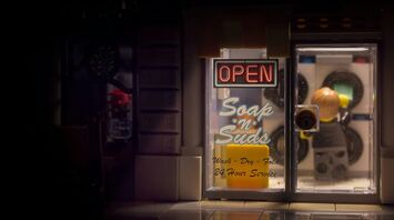 A warmly lit storefront window at night with a neon 'OPEN' sign