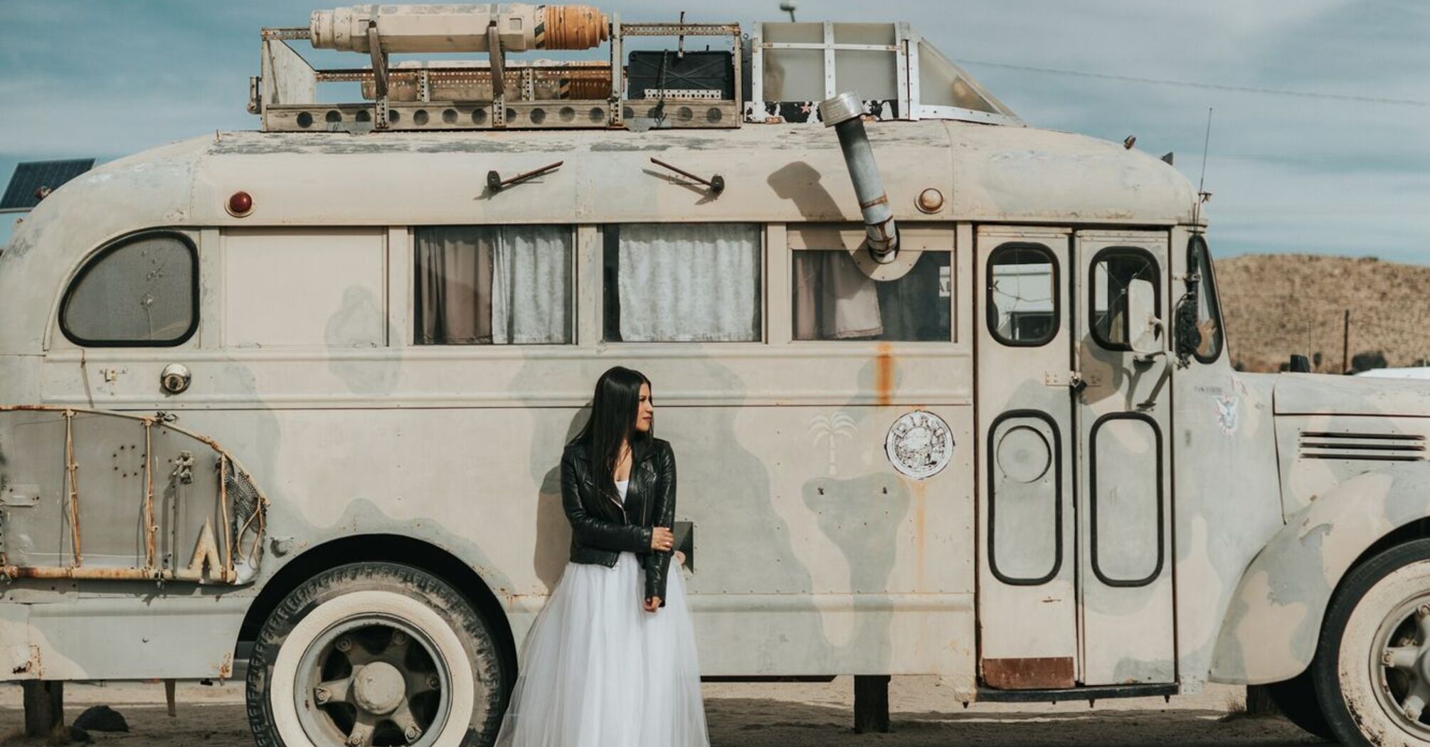 Woman in wedding dress standing next to white rv