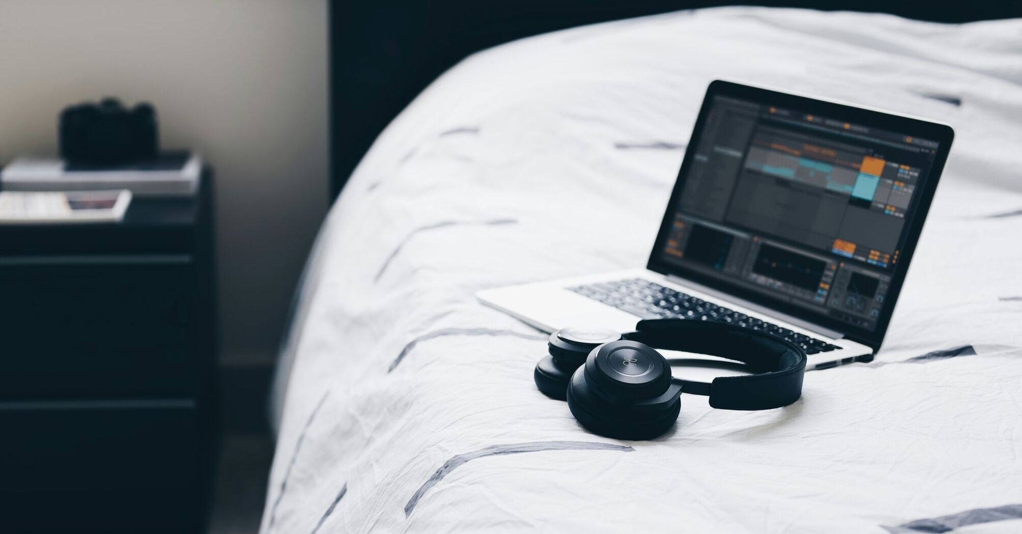 Laptop and headphones on a hotel bed
