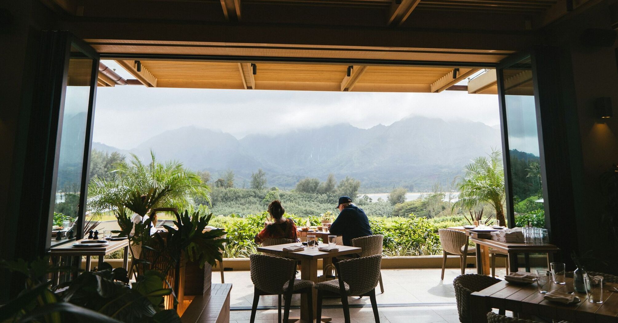 1 Hotel Hanalei Bay, View from a hotel terrace with diners overlooking lush green mountains