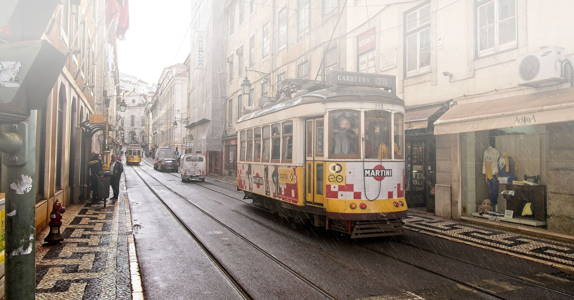 The photograph of a narrow street with people and transport, conveying the atmosphere of Lisbon