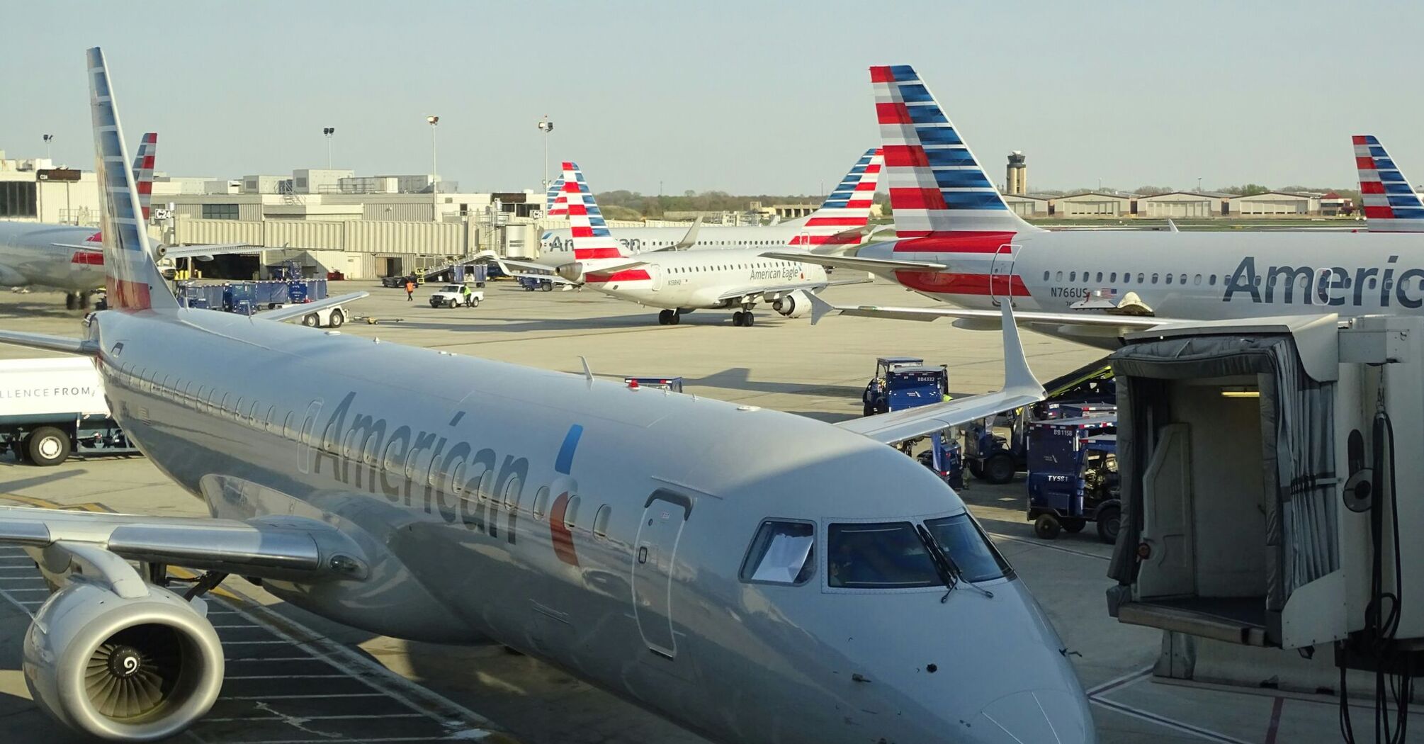 American Airlines aircraft at an airport gate and service vehicles in the background