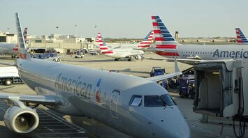 American Airlines aircraft at an airport gate and service vehicles in the background